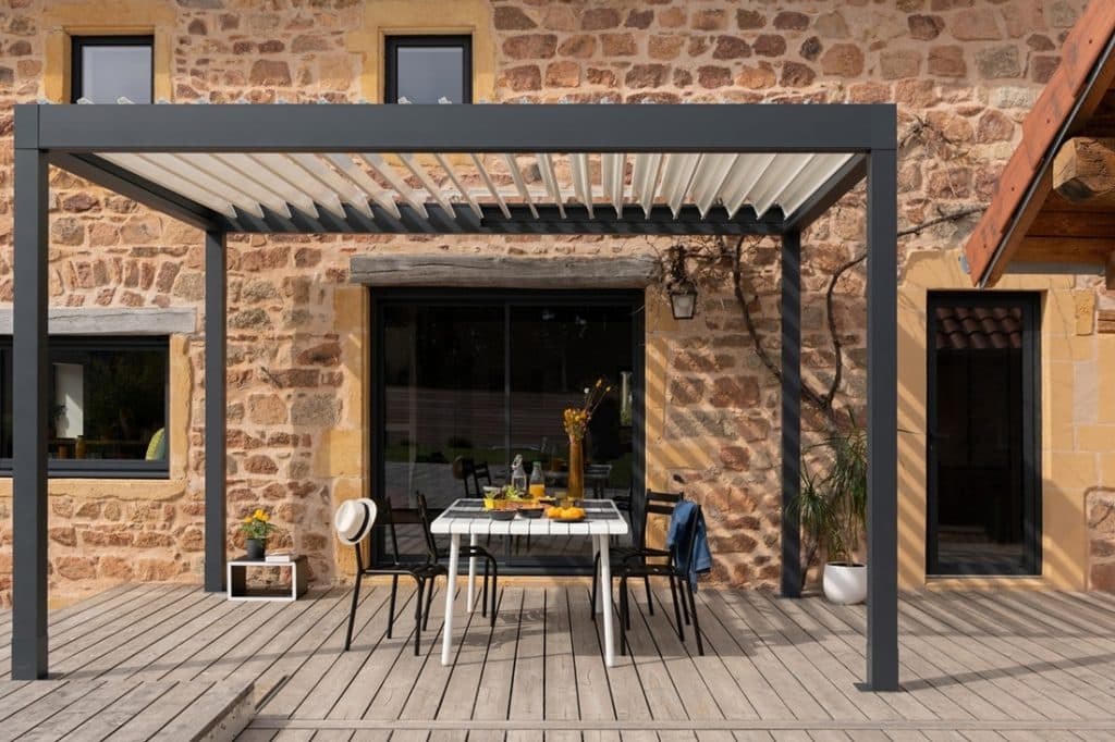 Pergola bioclimatique M110 installée devant une maison en pierre