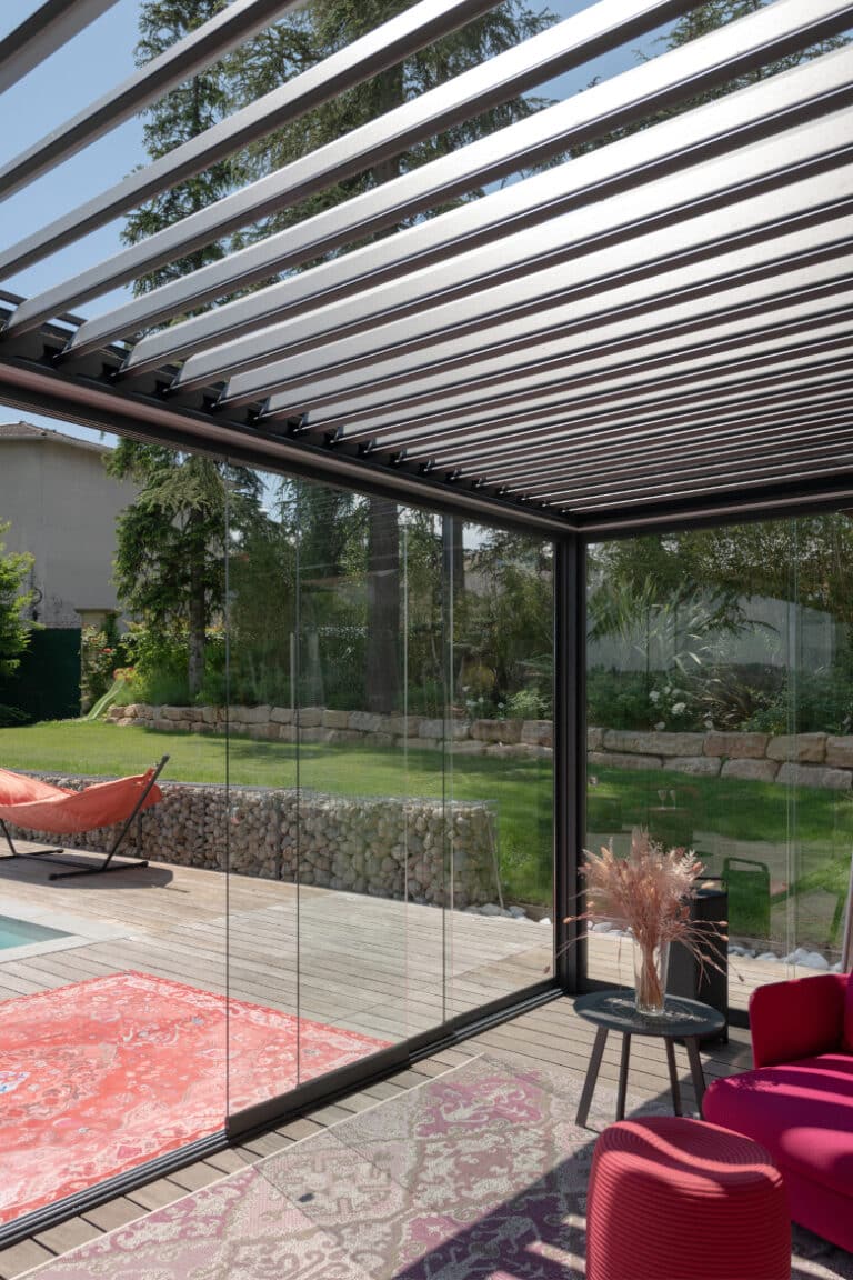 Pergola M130 avec vitrage panoramique M10, fusionnant les espaces intérieurs et extérieurs.